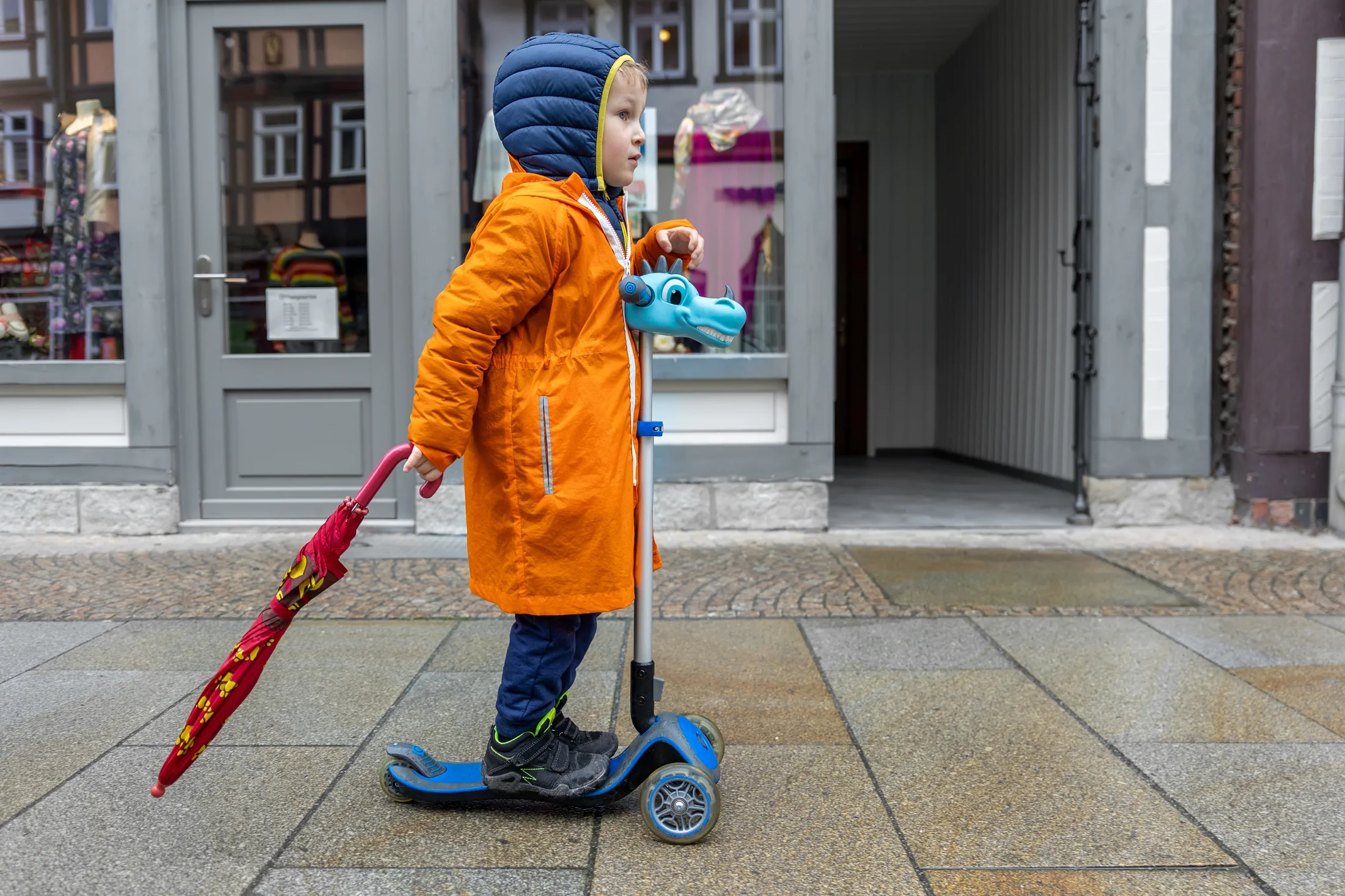 A child riding a scooter through a neighborhood street